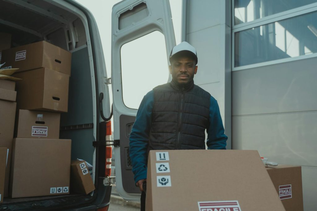 A delivery man unloads boxes from a van, showcasing logistics in action.