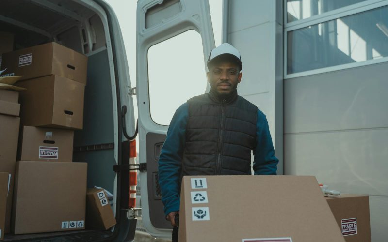 A delivery man unloads boxes from a van, showcasing logistics in action.